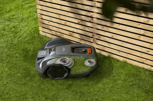 305E EdgeCut Robotic lawn mower on grass next to a wooden fence