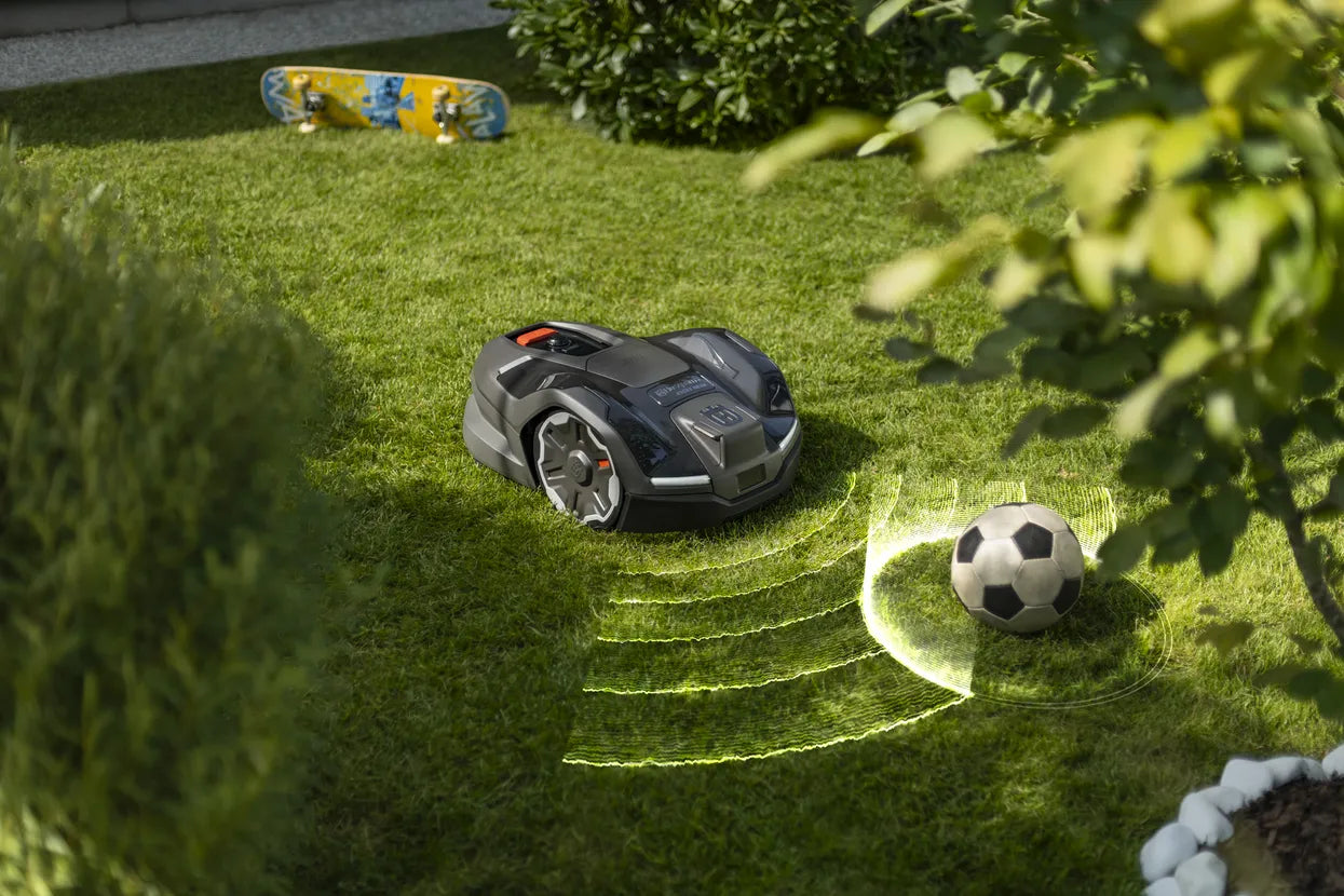 405XE Robotic lawn mower on a grassy lawn with a soccer ball and skateboard in the background