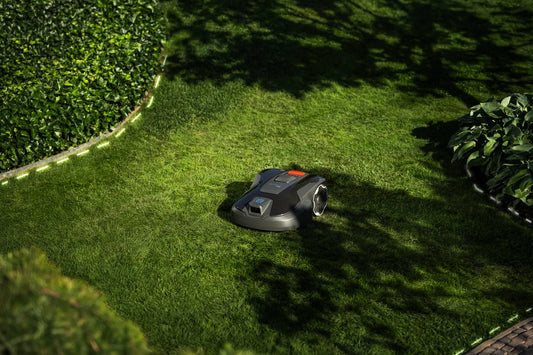 Robotic lawn mower on a green lawn with trees in the background