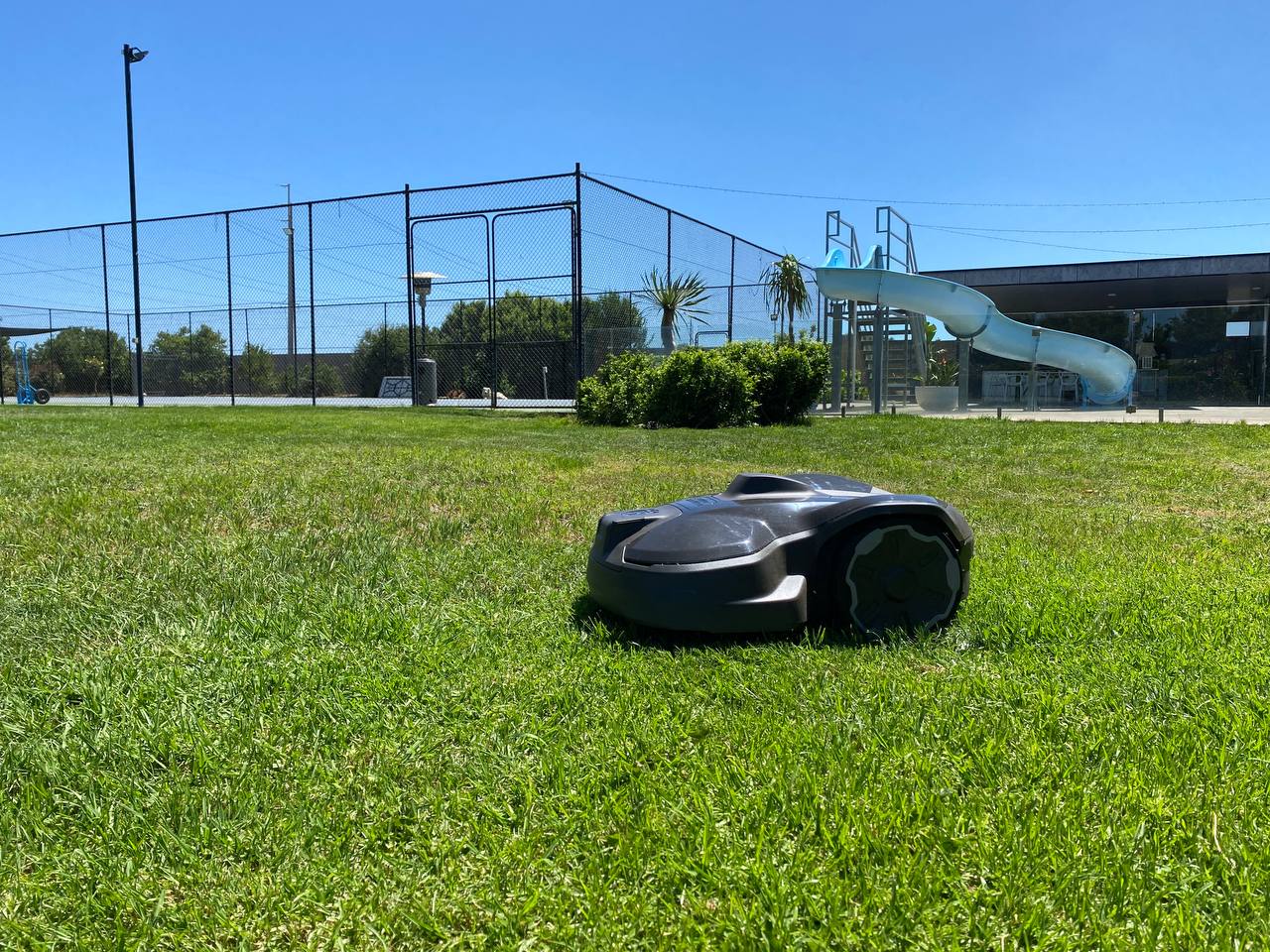 Husqvarna Automower 320 NERA on a grassy area with playground equipment in the background in Penfield Gardens-South Australia