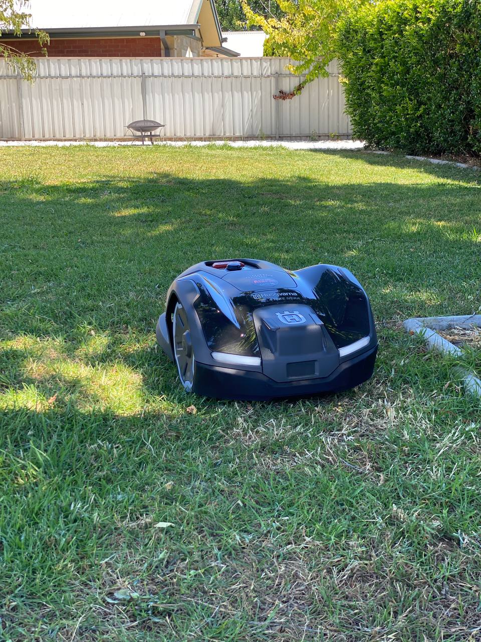 Husqvarna Automower 410XE on a grassy lawn with a house and fence in the background in Royston Park-South Australia