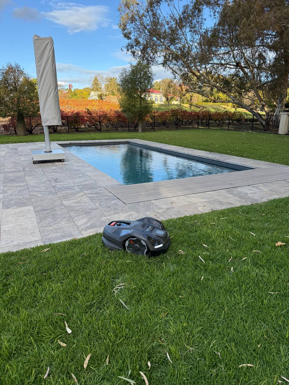 Husqvarna Automower 410XE on grass near a pool with a scenic background at Le Mas Barossa-South Australia