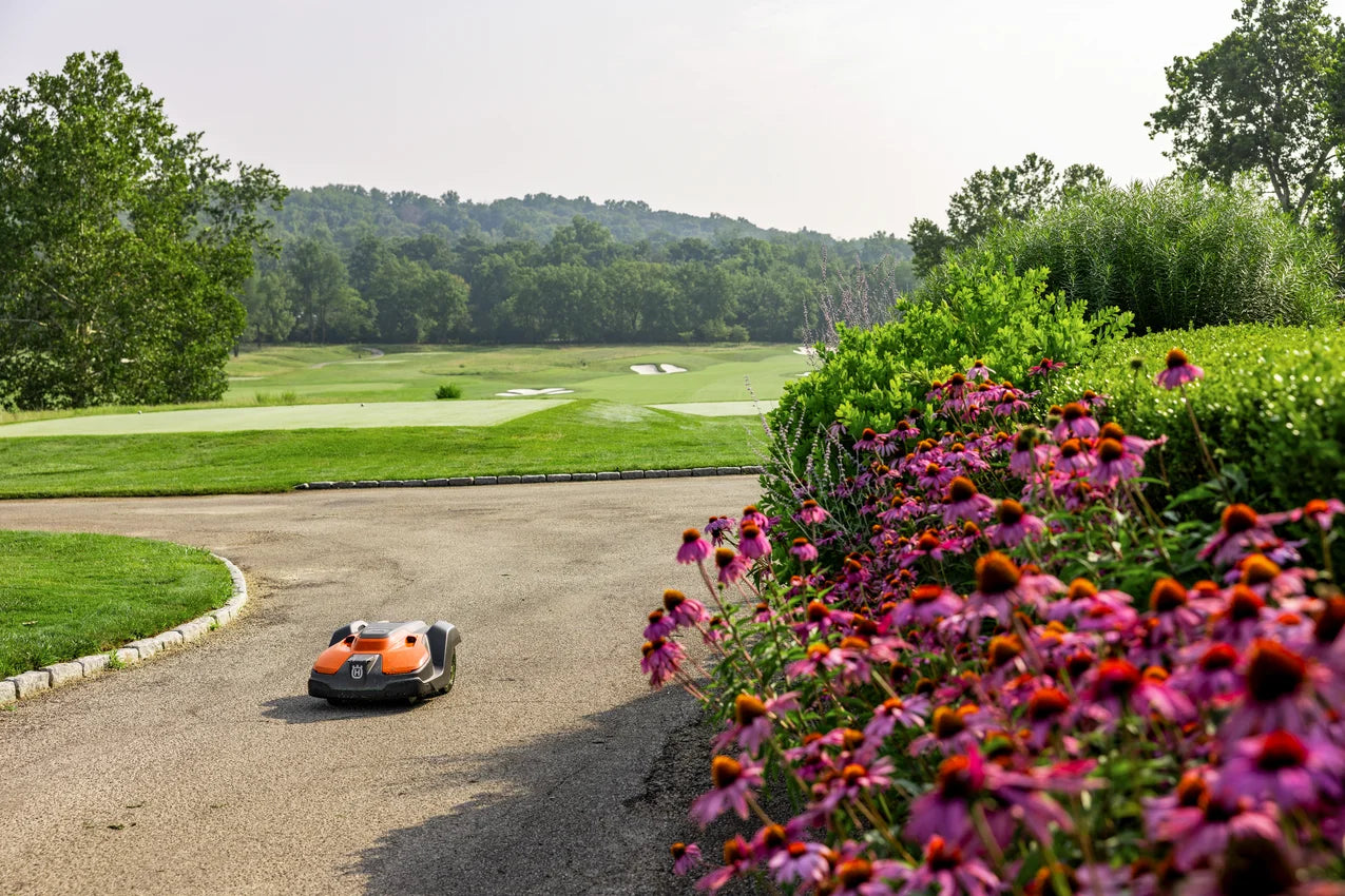 Automower 550 EPOS robot Lawn mower on a road with a golf course and trees in the background