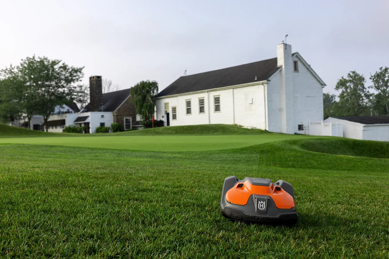 Automower 550 EPOS Commercial Robotic lawn mower on a grassy lawn with a white building in the background