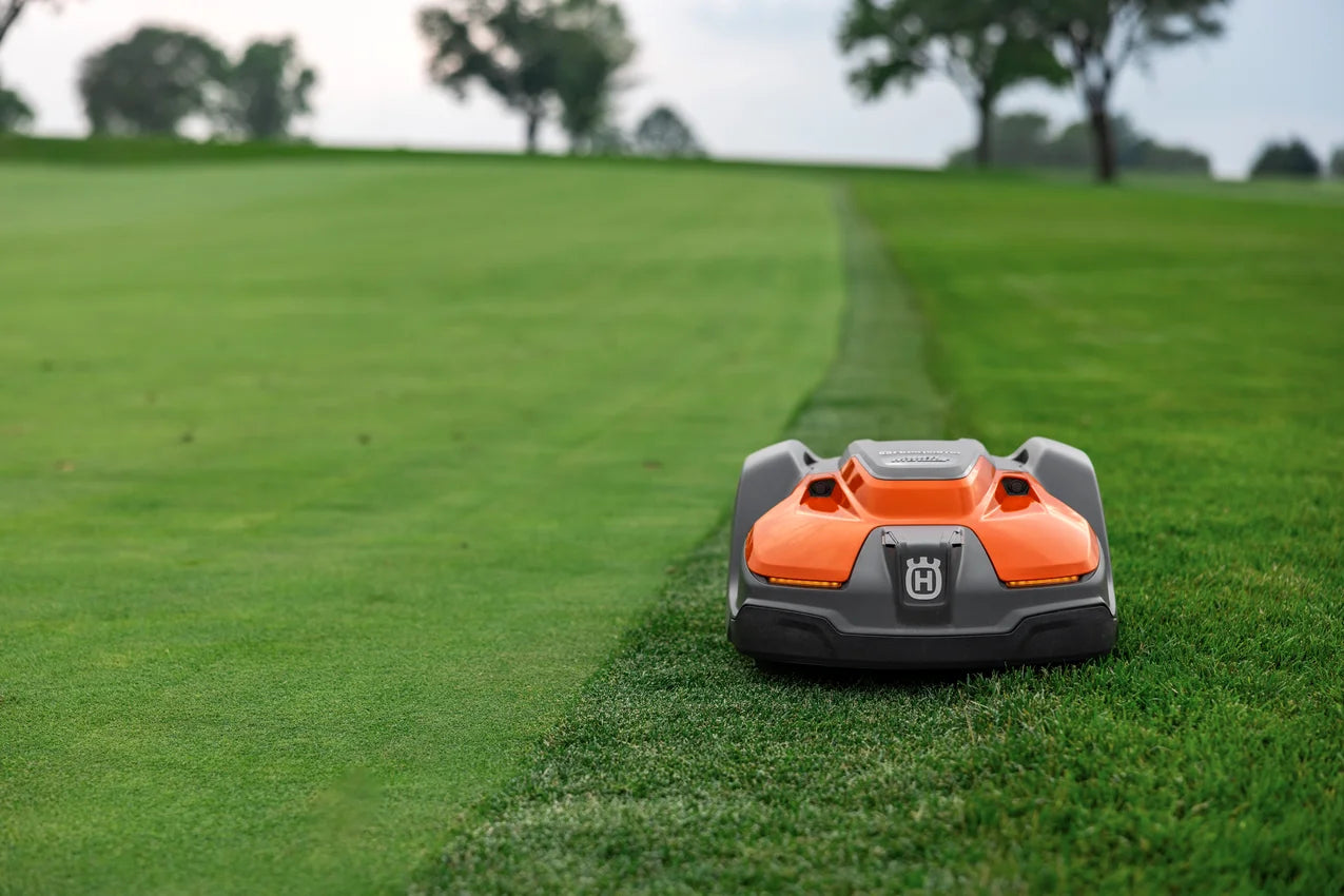 Automower 550 EPOS Commercial robotic lawn mower cutting grass on a green lawn with trees in the background