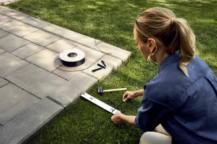 Woman install boundary wire with plastick pegs and rubber hammer