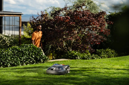 Person standing in a garden with a Automower 312V Husqvarna 970 83 11-06 on the grass