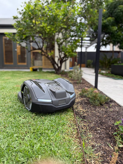 Husqvarna Automower 410XE EdgeCut on a grassy lawn with a house in the background in Brighton-South Australia