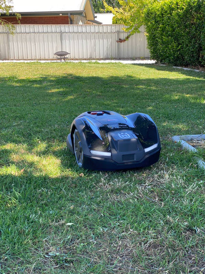 Husqvarna Automower 410XE on a grassy lawn with a house and fence in the background in Royston Park-South Australia