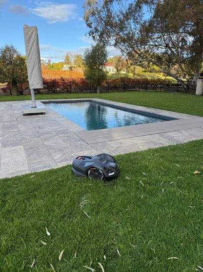 Husqvarna Automower 410XE on grass near a pool with a scenic background at Le Mas Barossa-South Australia