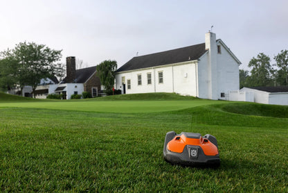 Automower 550 EPOS Commercial Robotic lawn mower on a grassy lawn with a white building in the background